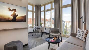 Ein modernes Wohnzimmer mit großem Fenster, einer Couch, einem kleinen Tisch und einem Sessel.