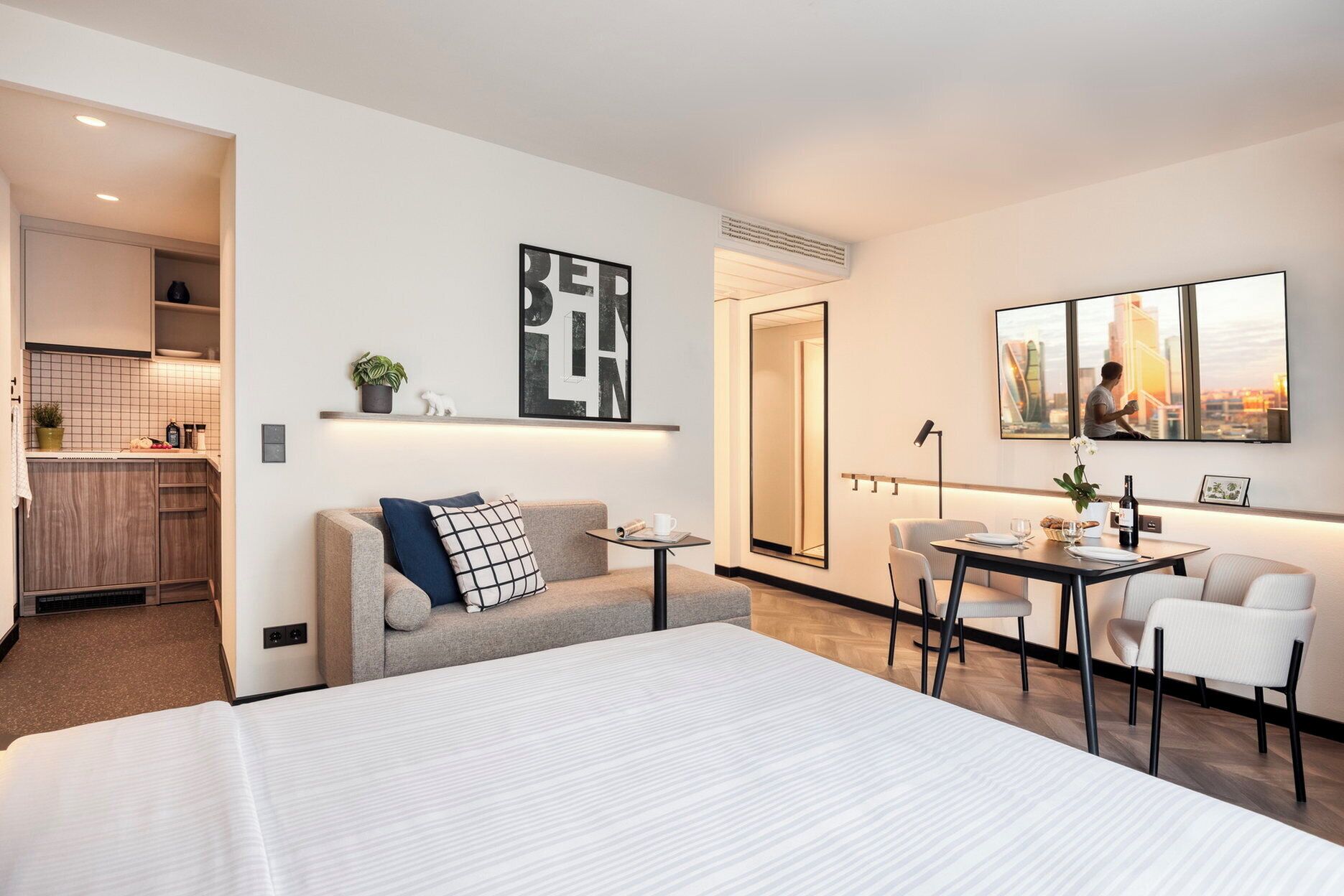 Et moderne hotelværelse med seng, sofa, spisebord og et tekøkken.