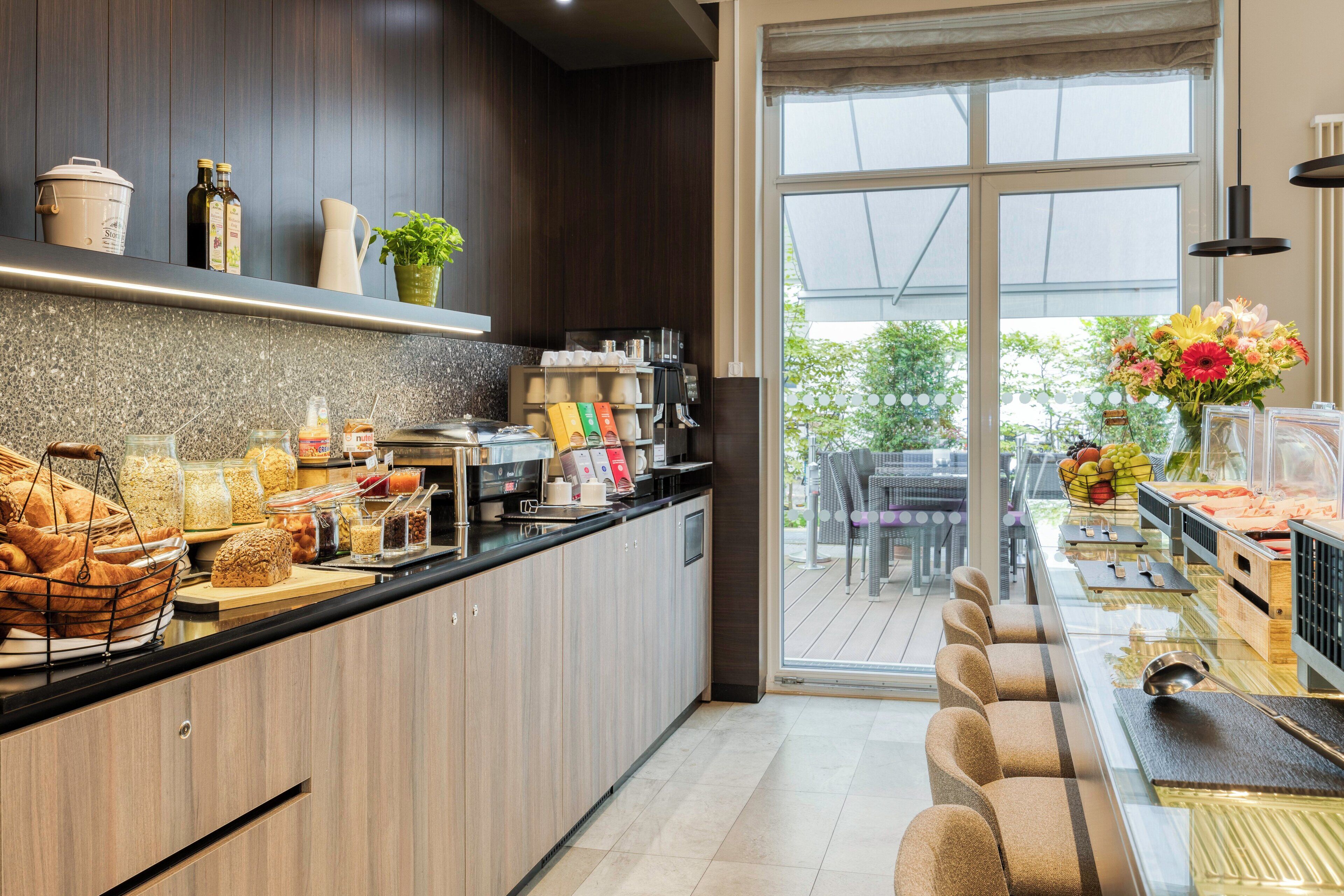 A modern kitchen with a breakfast bar, various food items, and a view of the outdoors.