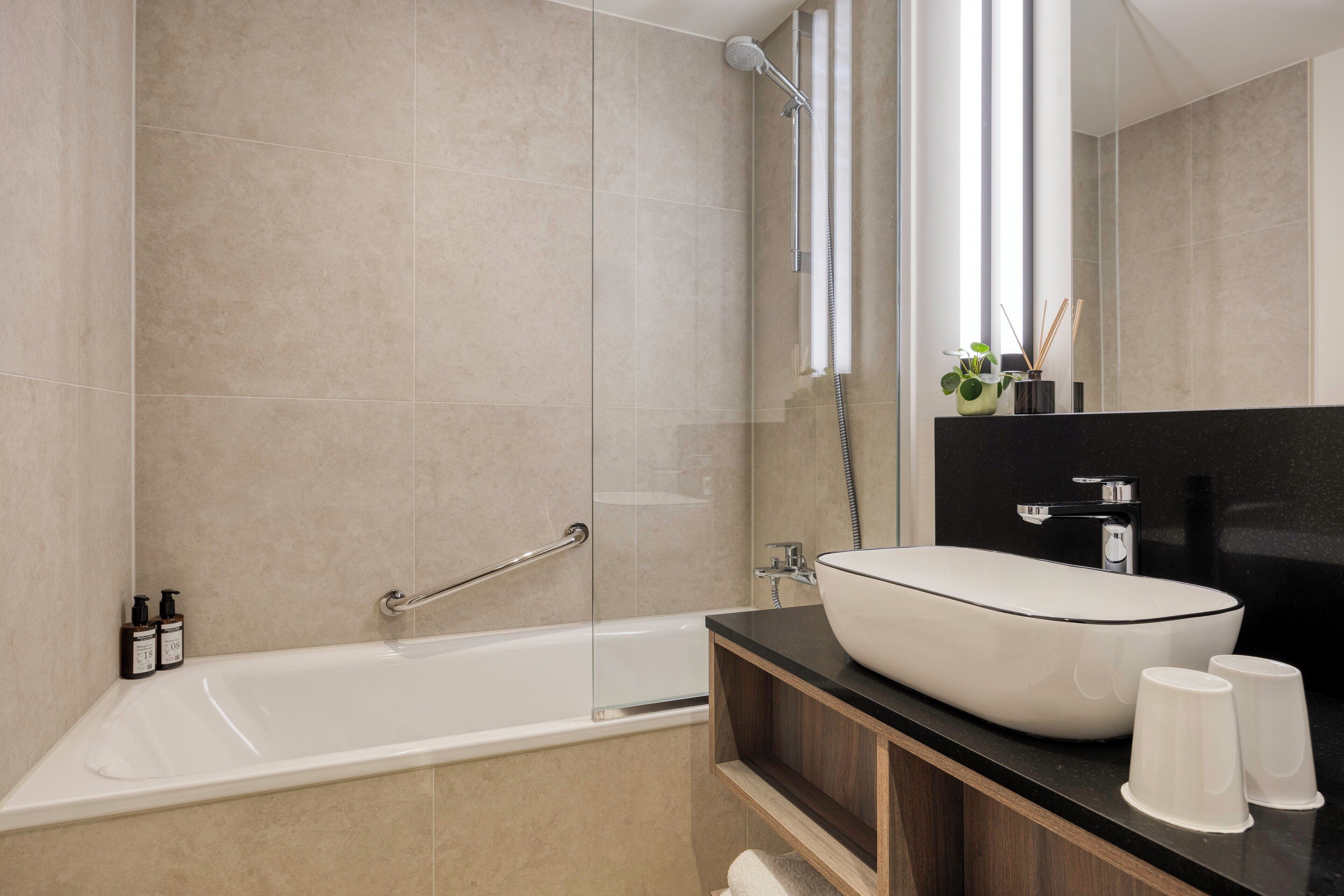 Un bagno moderno con una vasca, uno specchio grande e un mobile lavabo.
