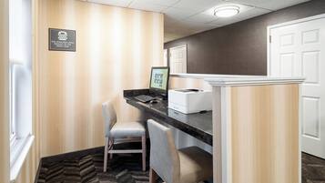 A reception area with a computer, two chairs, a counter, and a door.
