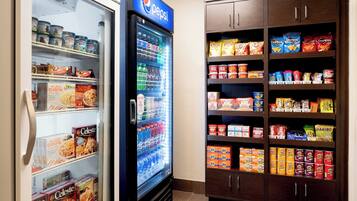 A vending machine stocked with snacks and a refrigerator with beverages.