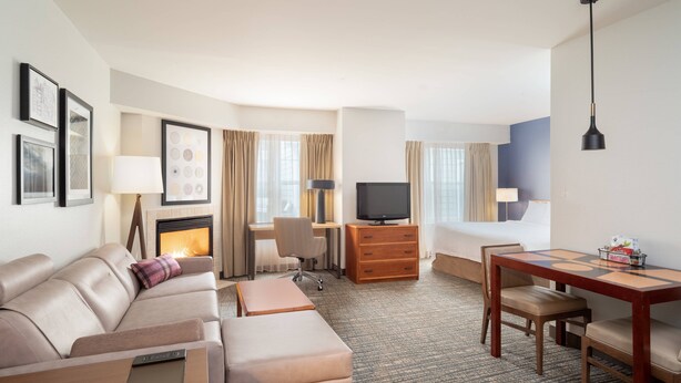 A hotel room with a sofa, a desk, a television, a fireplace, and a dining table. - Residence Inn by Marriott New Bedford Dartmouth (North Dartmouth)