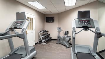 A fitness room with treadmills, a television, and a dumbbell rack.