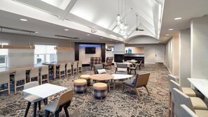 A modern hotel lobby with a high ceiling, recessed lighting, and a mix of seating arrangements including tables and chairs. - Residence Inn by Marriott New Bedford Dartmouth (North Dartmouth)