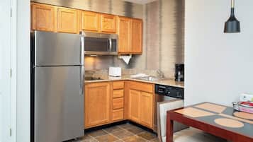 A compact kitchen with wooden cabinets, stainless steel appliances, and a dining area with a table and chairs.