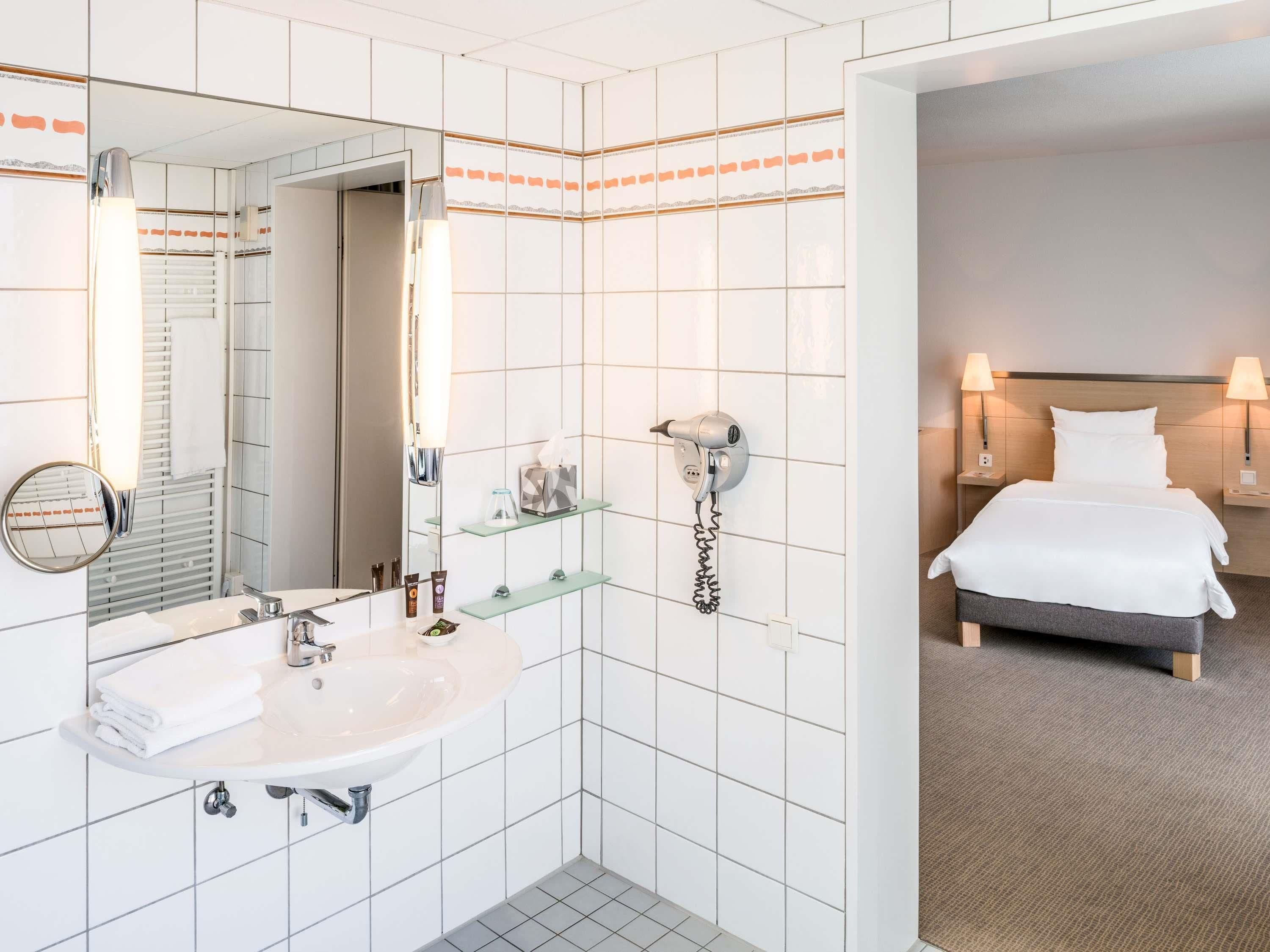 Ein Badezimmer mit Waschbecken, Spiegel und Fön an der Wand.