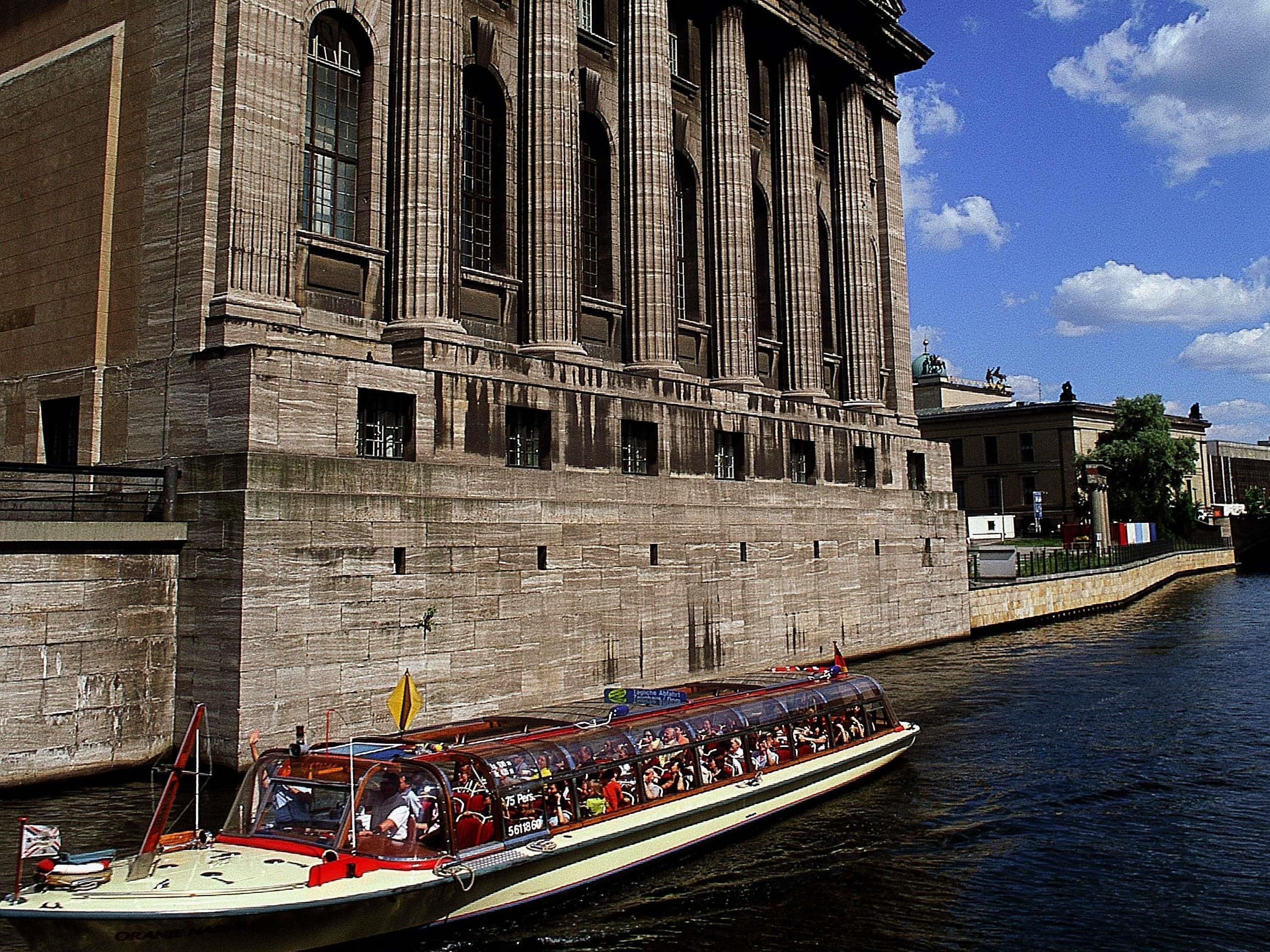 A large stone building with arched windows and a boat with passengers.