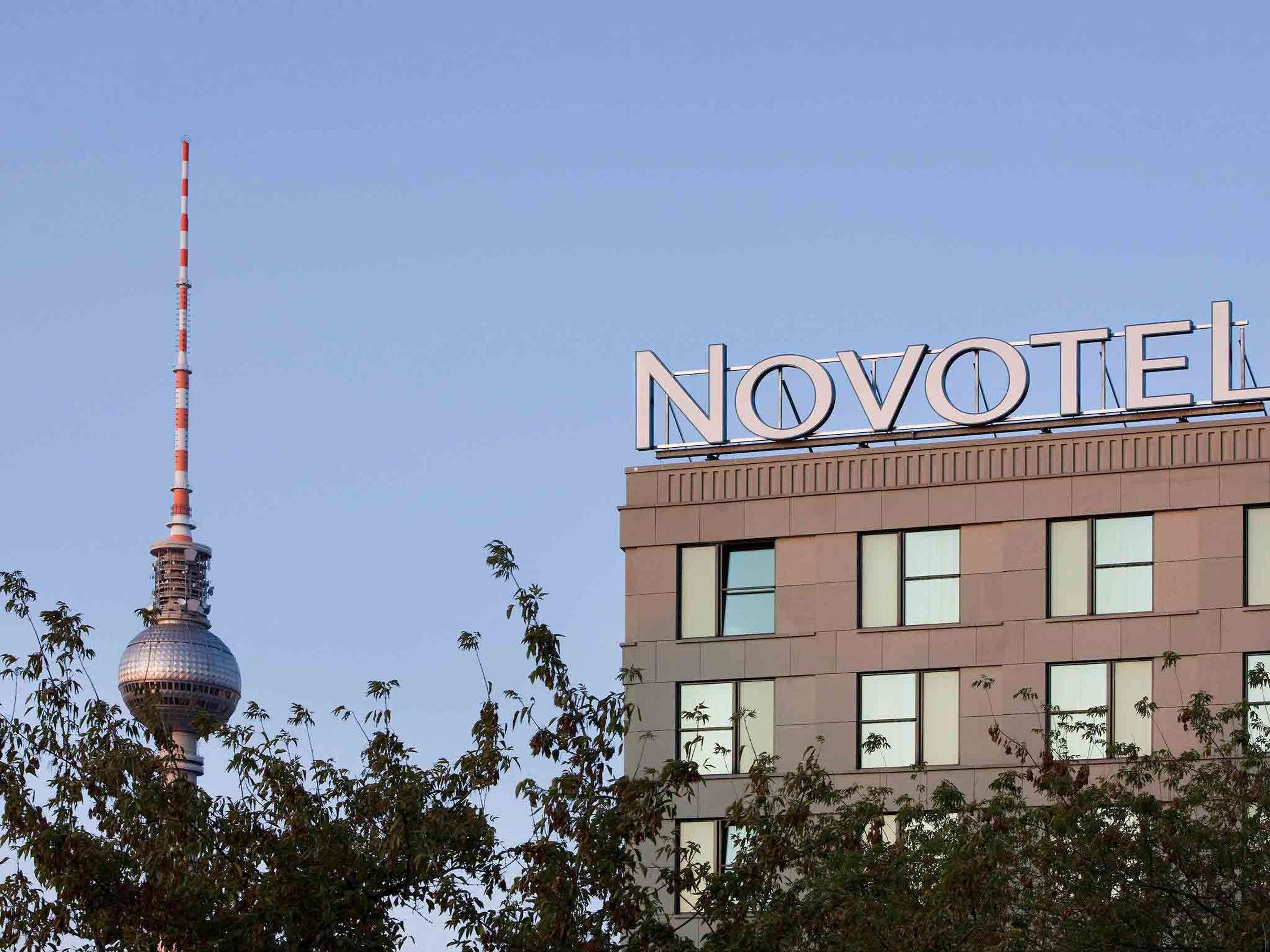 Un hotel con un letrero llamativo, una torre alta y árboles circundantes.