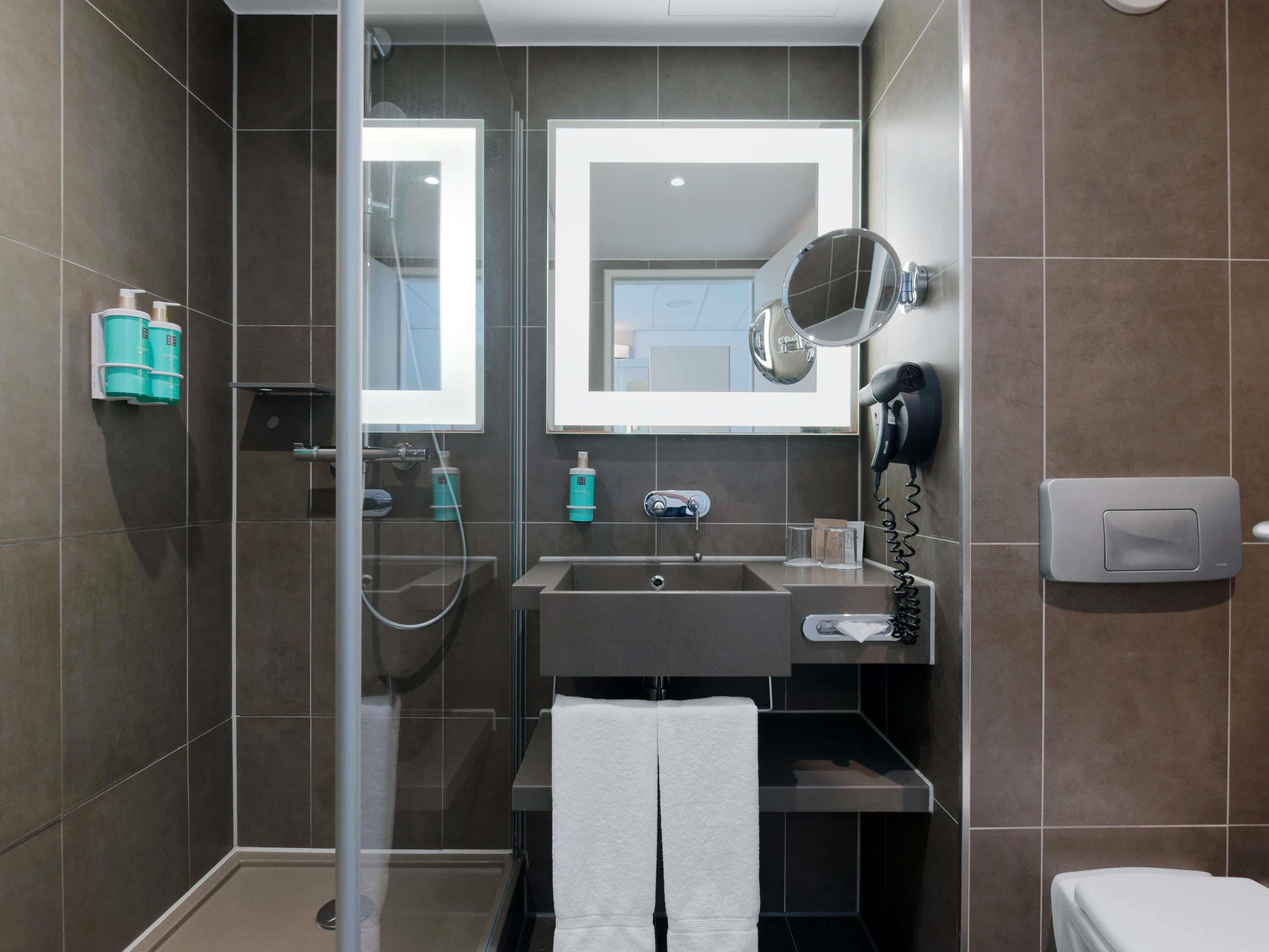 Ein modernes Badezimmer mit Duschkabine aus Glas, Waschbecken mit Spiegel und Toilette.
