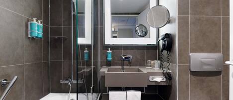 Un baño moderno con ducha de vidrio, lavamanos con espejo y un inodoro.
