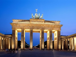 Un edificio grande e histórico con una entrada destacada que presenta altas columnas y una escultura central.