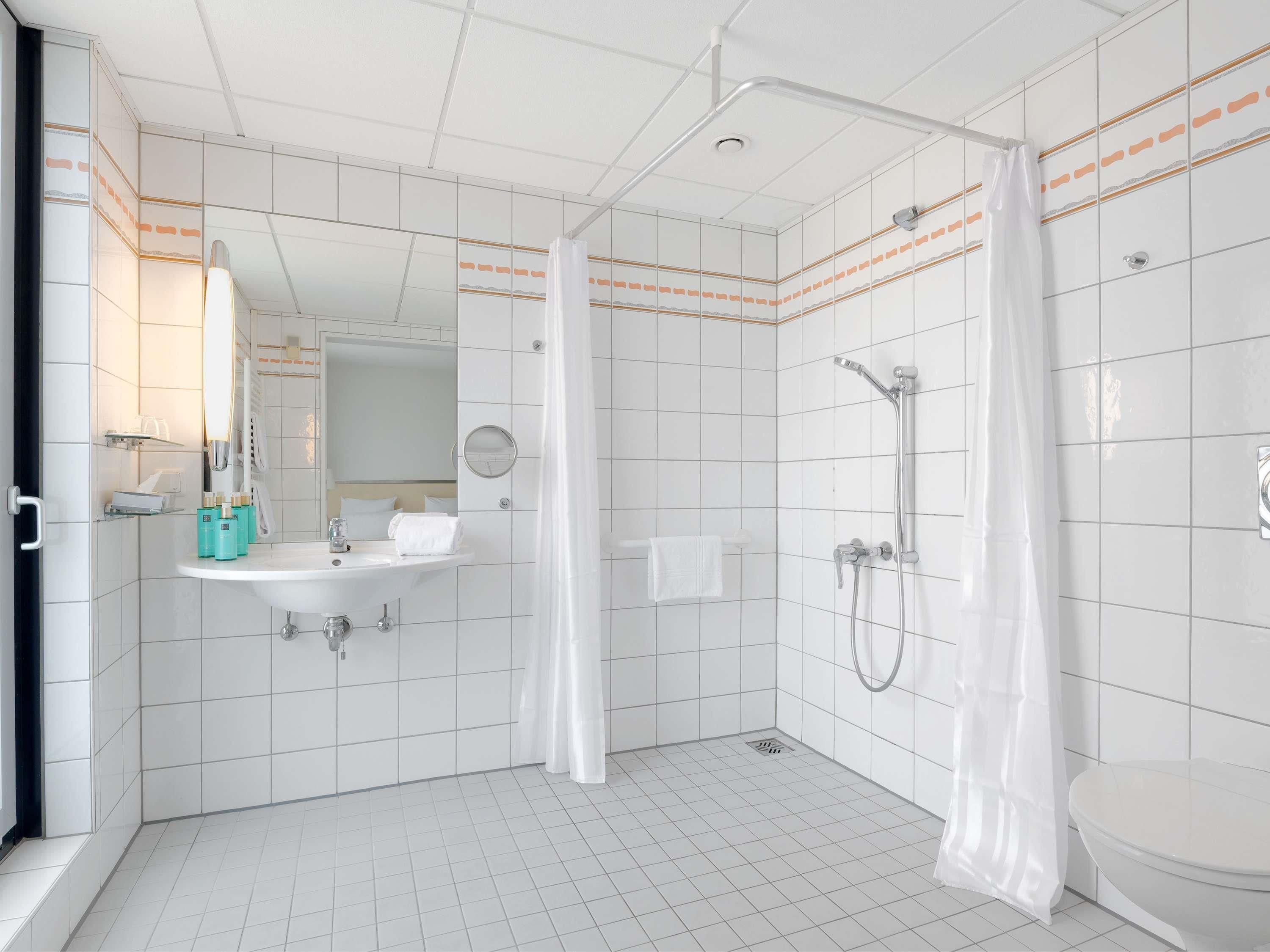 Un baño moderno con ducha, inodoro, lavabo y espejo.