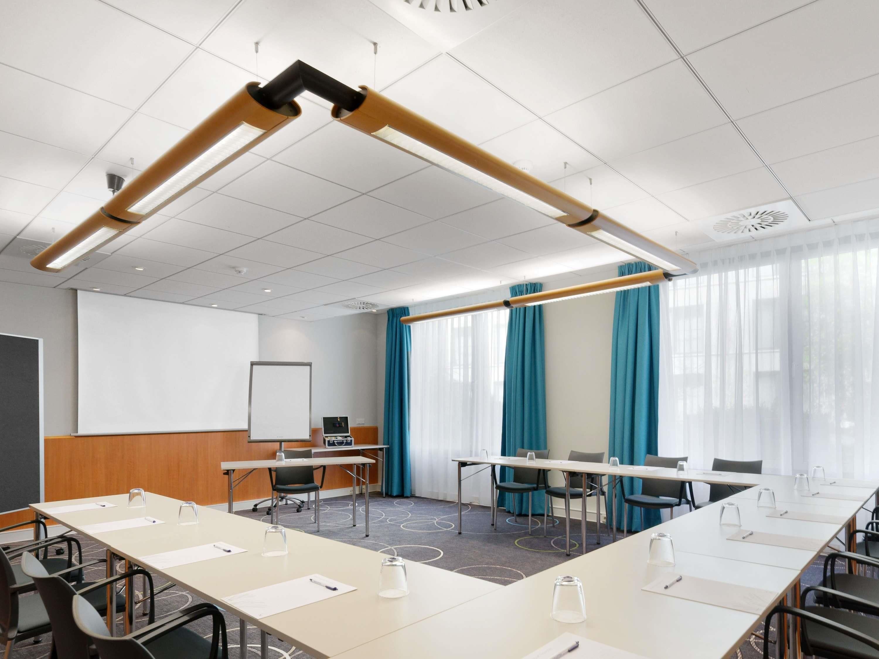 A conference room with a long table, chairs, a projector screen, and a whiteboard.