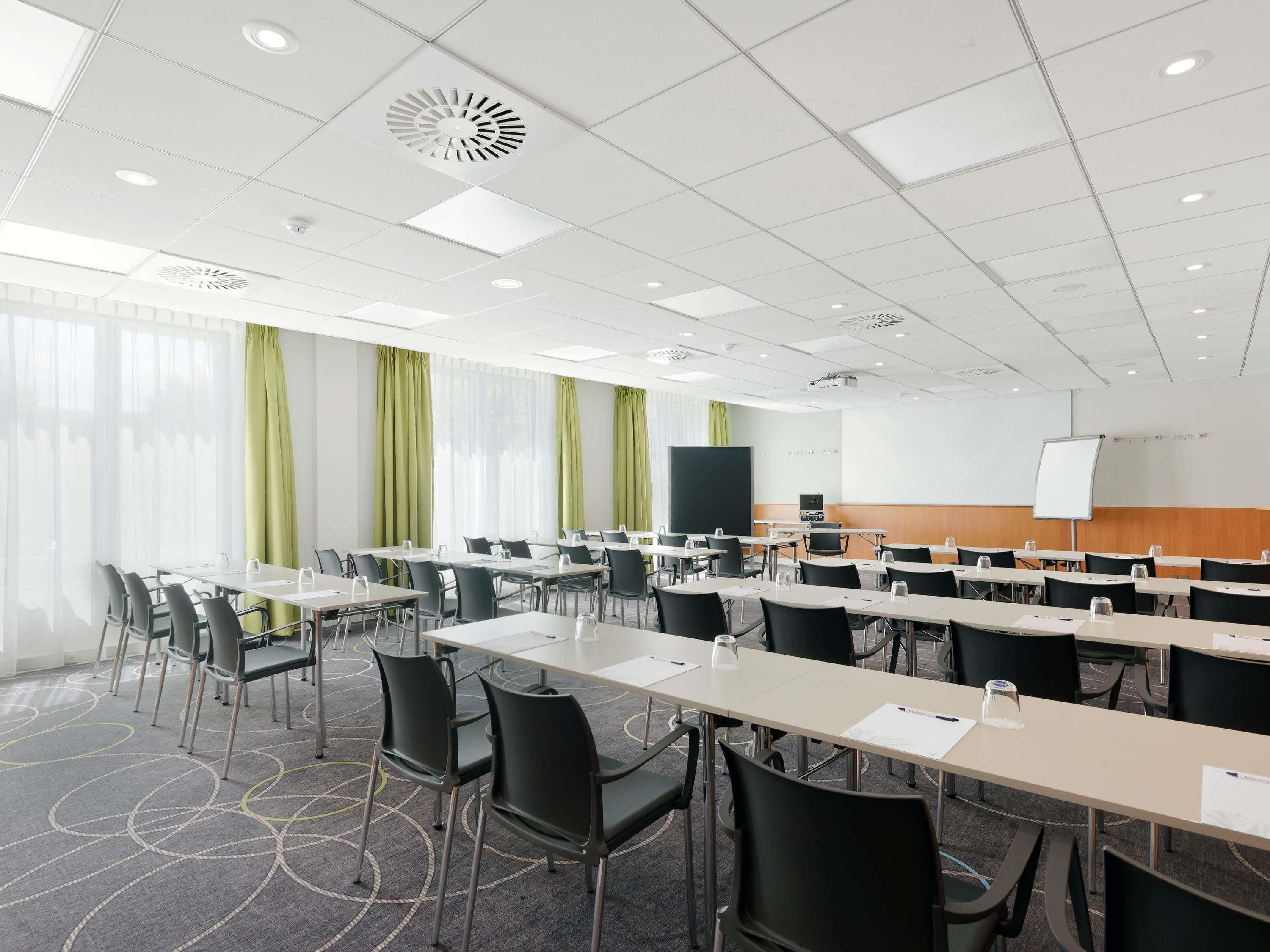 A conference room with tables, chairs, a projector, and a whiteboard.