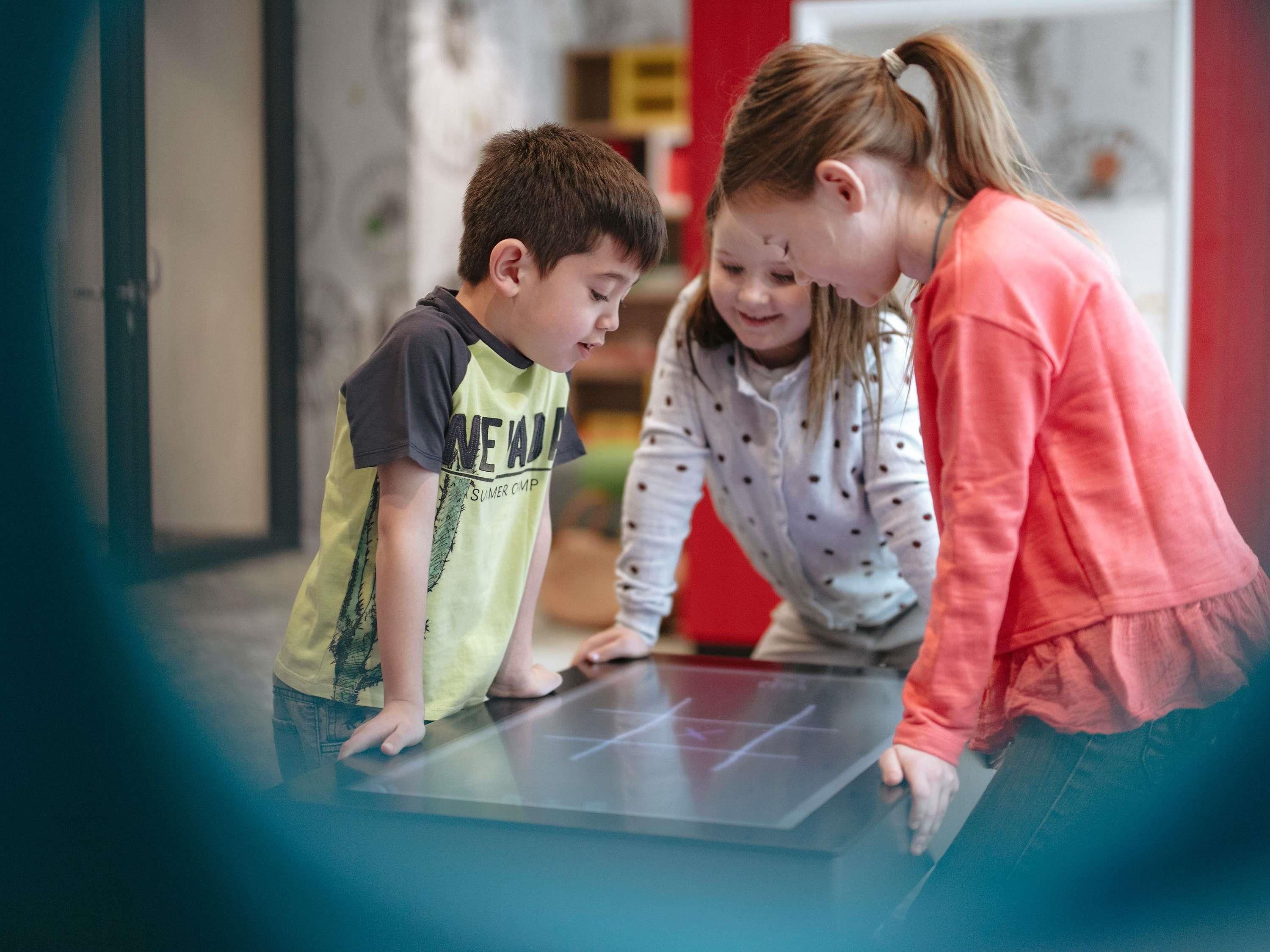 Un niño y un adulto interactúan con una pantalla digital.