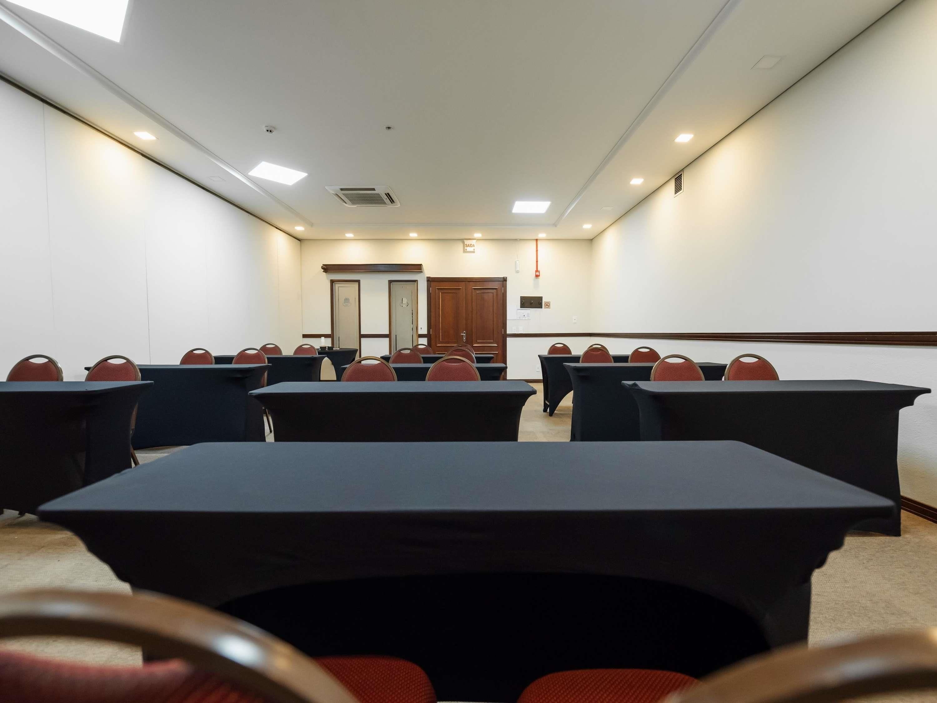 Ein Konferenzraum mit Tischen, Stühlen, einer Tafel und einer Tür im Hintergrund.