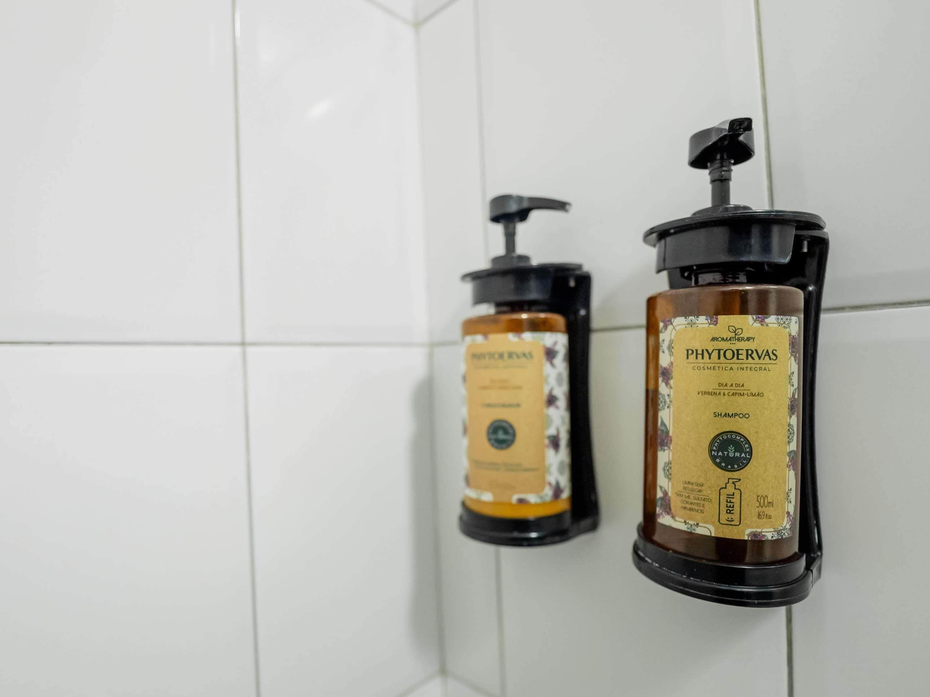 Dos botellas de artículos de aseo personal sujetas a una pared de azulejos.