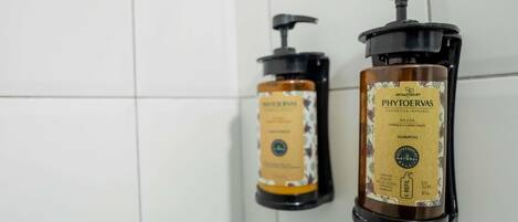 Dos botellas de artículos de aseo personal sujetas a una pared de azulejos.