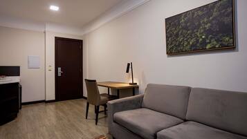 Uma sala de estar moderna com sofá, mesa de jantar com cadeira, um quadro na parede e uma porta.