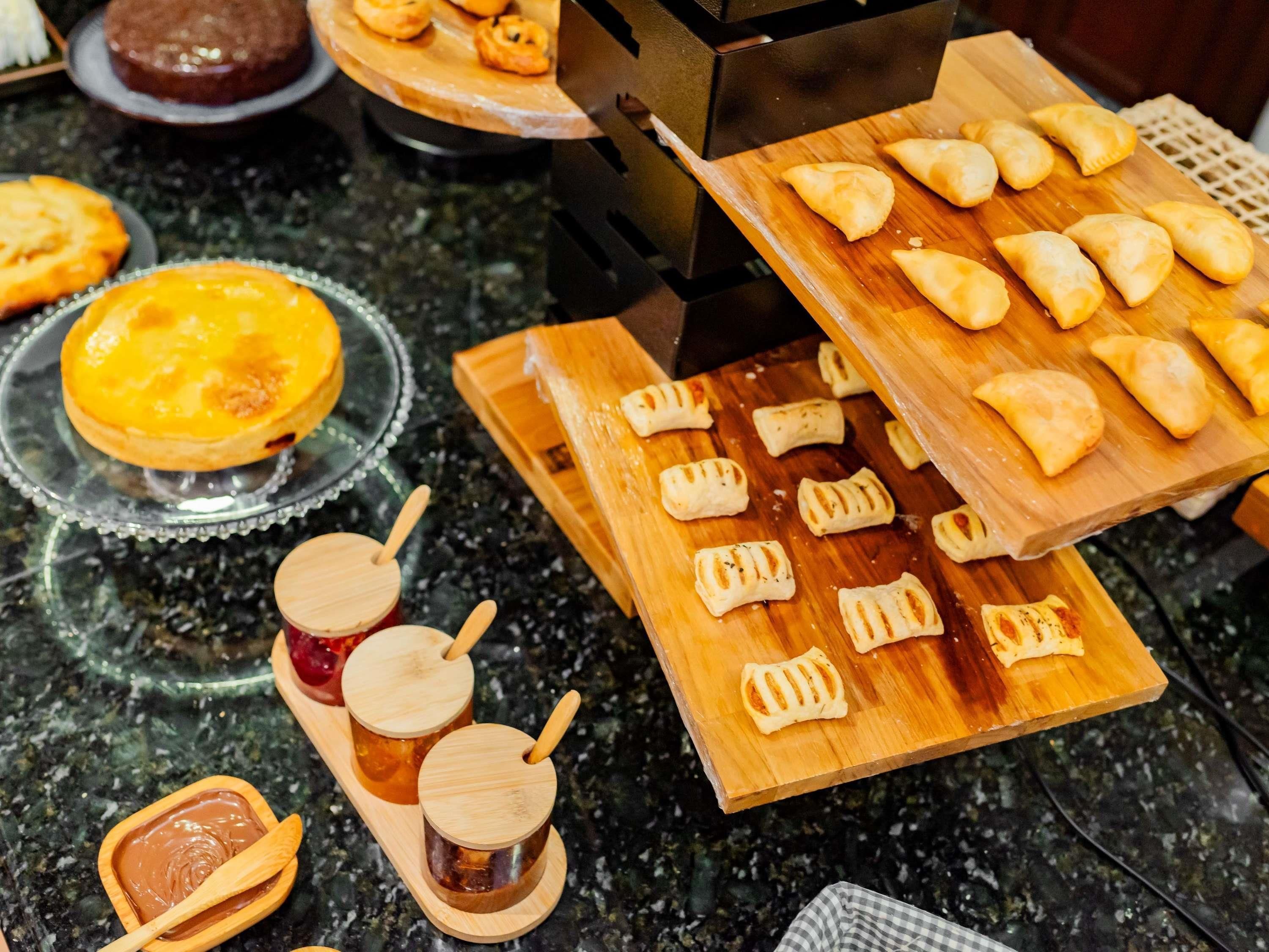 Una mesa de buffet con diversos alimentos, entre ellos bollería, un postre y bebidas.