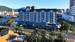 A multi-story hotel with a modern design, featuring balconies on each floor, a prominent entrance, and a view of the surrounding urban area. - Mercure Jaraguá do Sul Hotel (Jaragua do Sul)