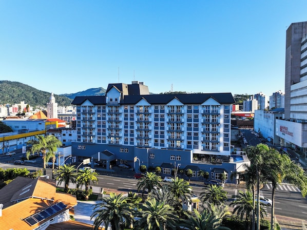 Un hotel de varios pisos con diseño moderno, que cuenta con balcones en cada planta, una entrada destacada y vistas del área urbana circundante.