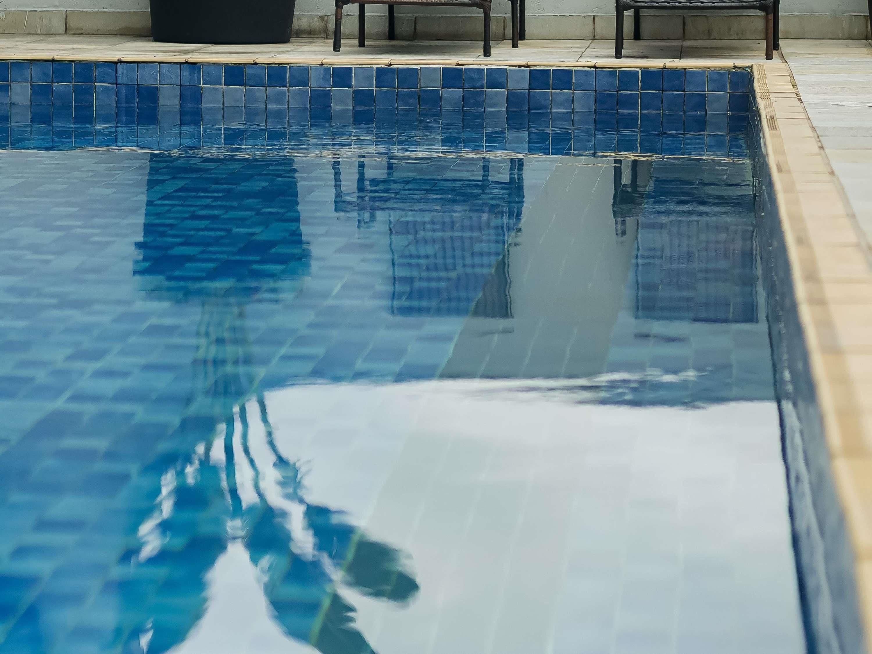 Una piscina con azulejos azules y borde enlosado.