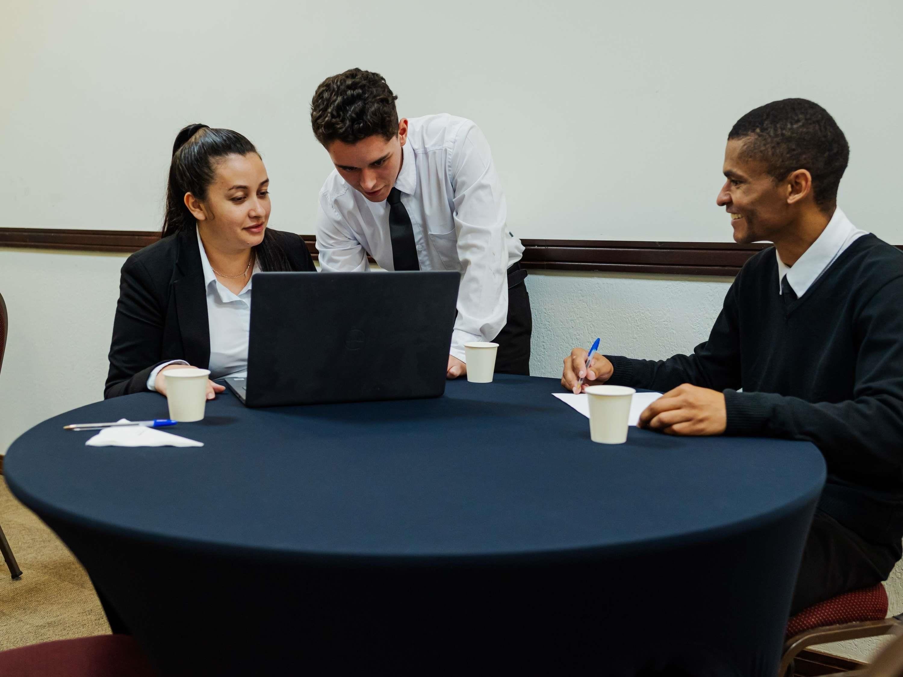 A round table with a laptop, papers, and coffee cups.