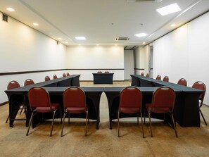 A conference room with a long table, red chairs, and a podium.