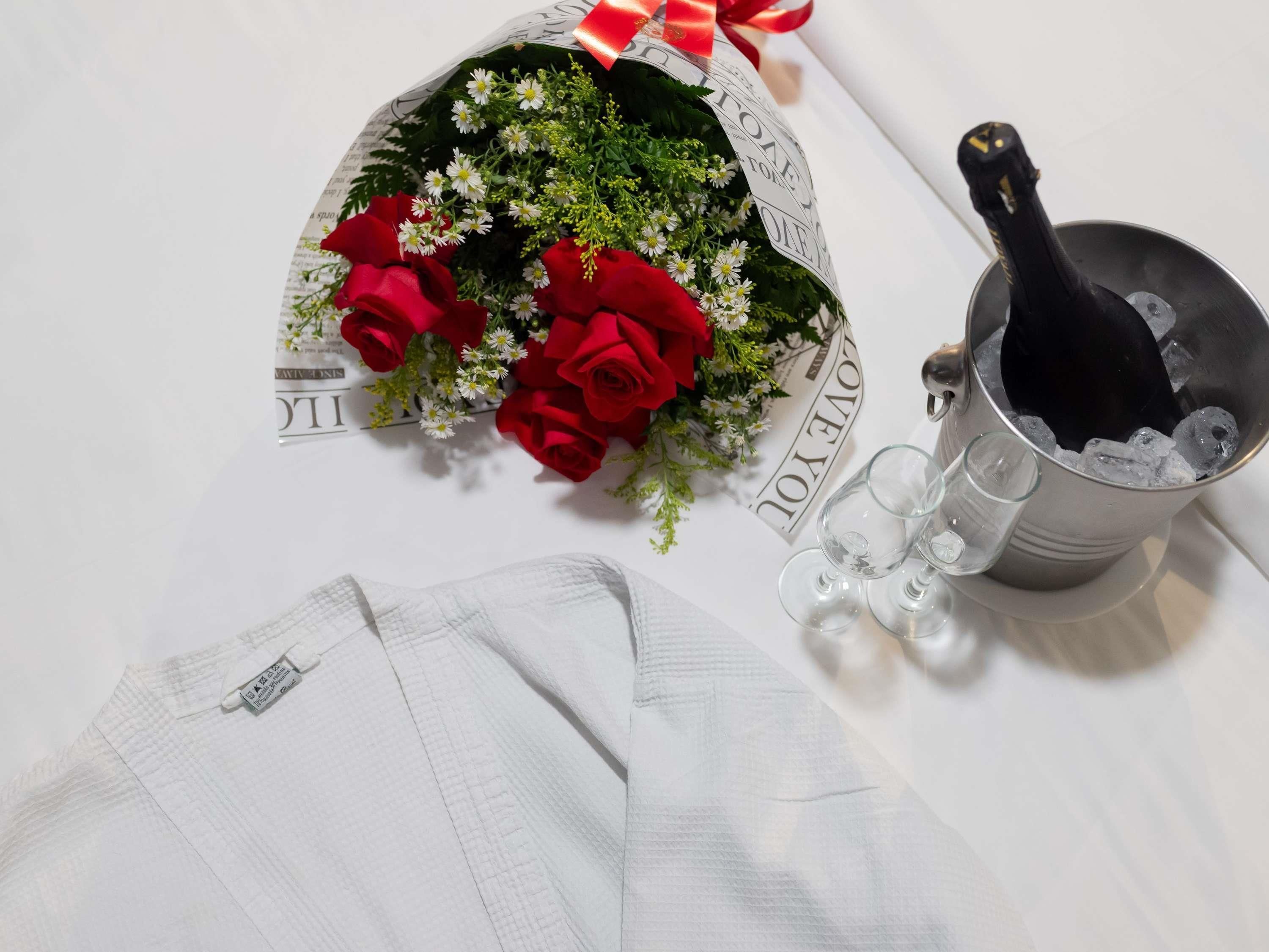 A bouquet of flowers, a bottle of champagne, and a glass of water on a table.
