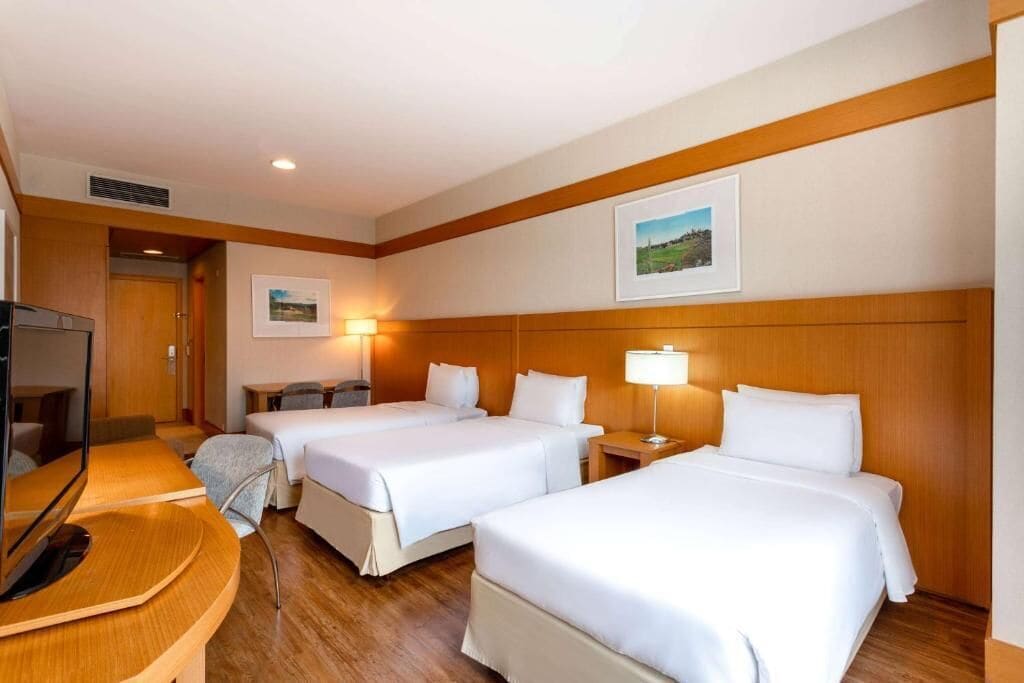 A hotel room with two beds, a desk, a TV, and a picture on the wall.