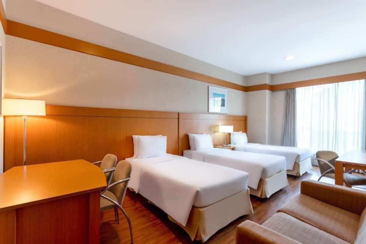 A hotel room with two beds, a desk, and a chair.