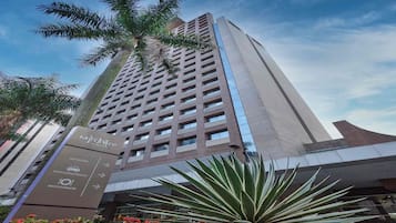 A tall hotel building with a modern design, featuring a reception area and a restaurant.
