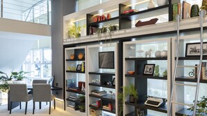 A modern interior with a high ceiling, a mezzanine level with bookshelves, and a seating area with chairs and a table. - Mercure Sao Paulo Bela Vista (São Paulo)