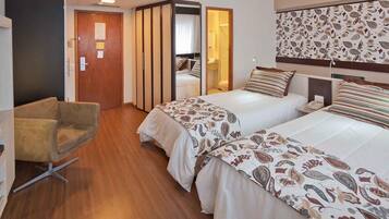 Une chambre d’hôtel avec deux lits, une chaise et une armoire.