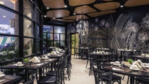 A modern restaurant with black furniture, wooden ceiling panels, and a wall mural of white floral designs. - Mercure Sao Paulo Bela Vista (São Paulo)
