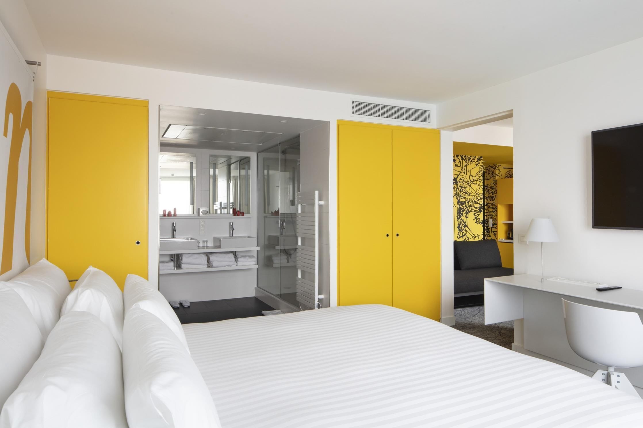 Una habitación de hotel moderna con una cama grande, un escritorio y un vestidor.