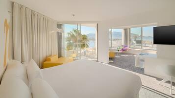 Habitación de hotel con una cama grande, un escritorio, una silla y un balcón con vistas.