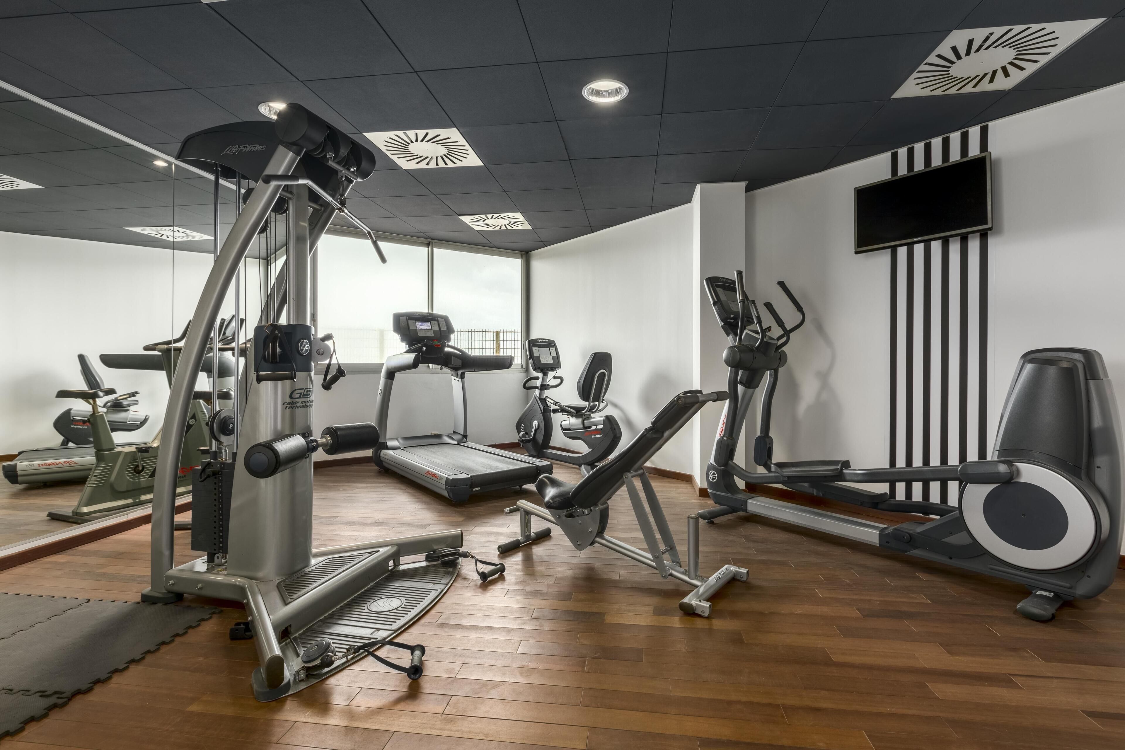 A gym with various exercise machines, a treadmill, and a stationary bike.