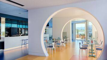 Un interior moderno con un arco circular, una zona de bar y un comedor con mesas y sillas.