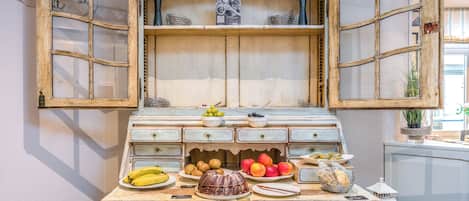 Un aparador de madera antiguo con puertas abiertas, una exposición de frutas y un farol.