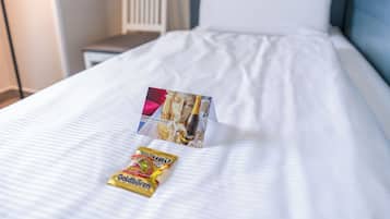 A neatly made bed with white linens, a small bedside table, and a lamp.