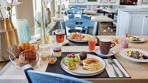 A breakfast setting with various food items, a coffee cup, and a vase with flowers.