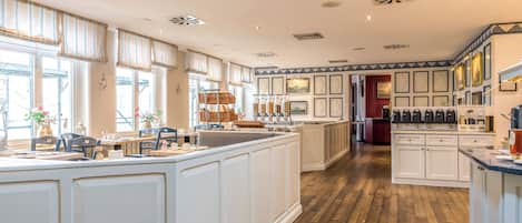A spacious kitchen with a large island, wooden flooring, and a view of the dining area.
