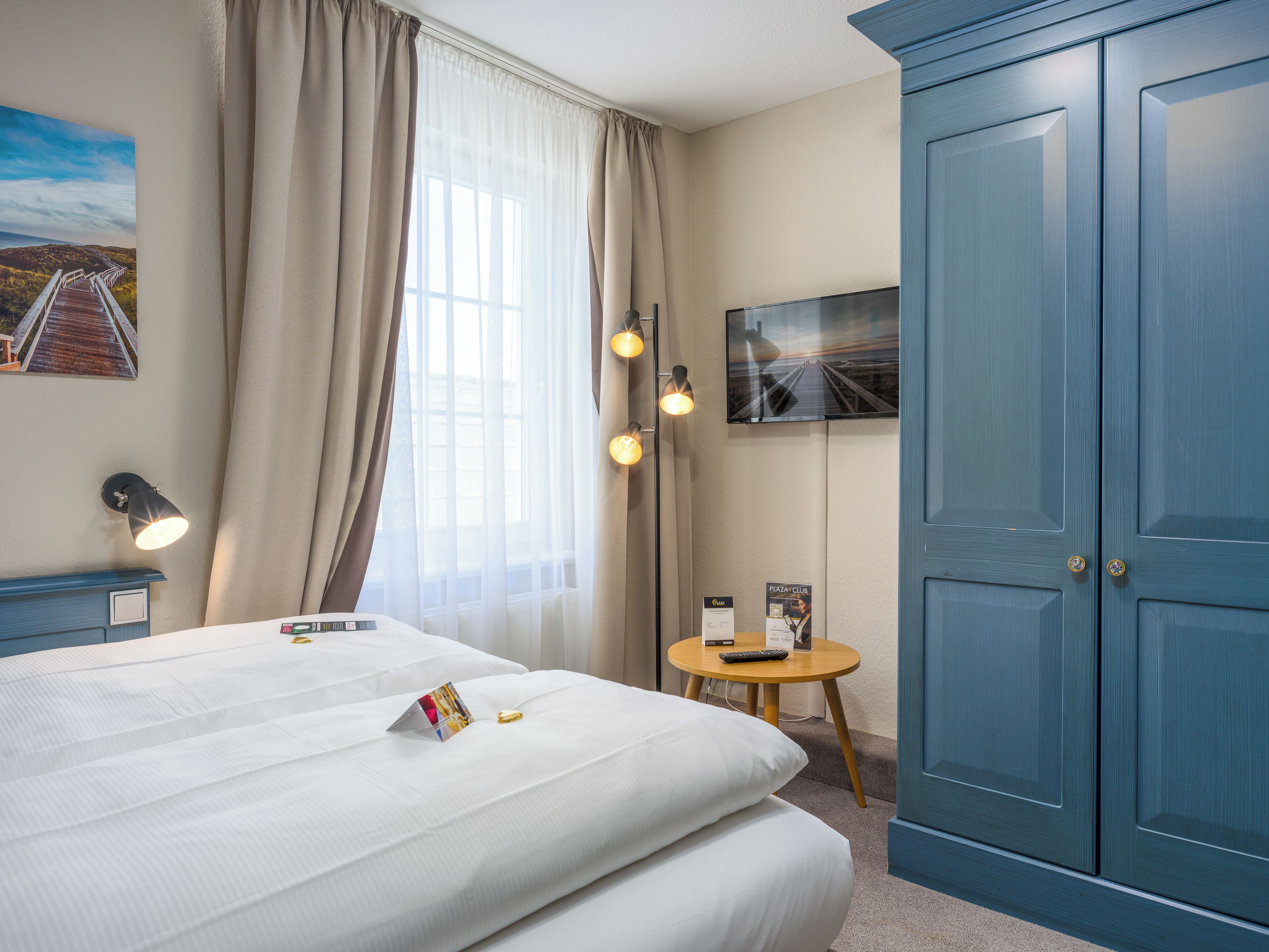 A hotel room with a bed, a desk, a television, and a wardrobe.
