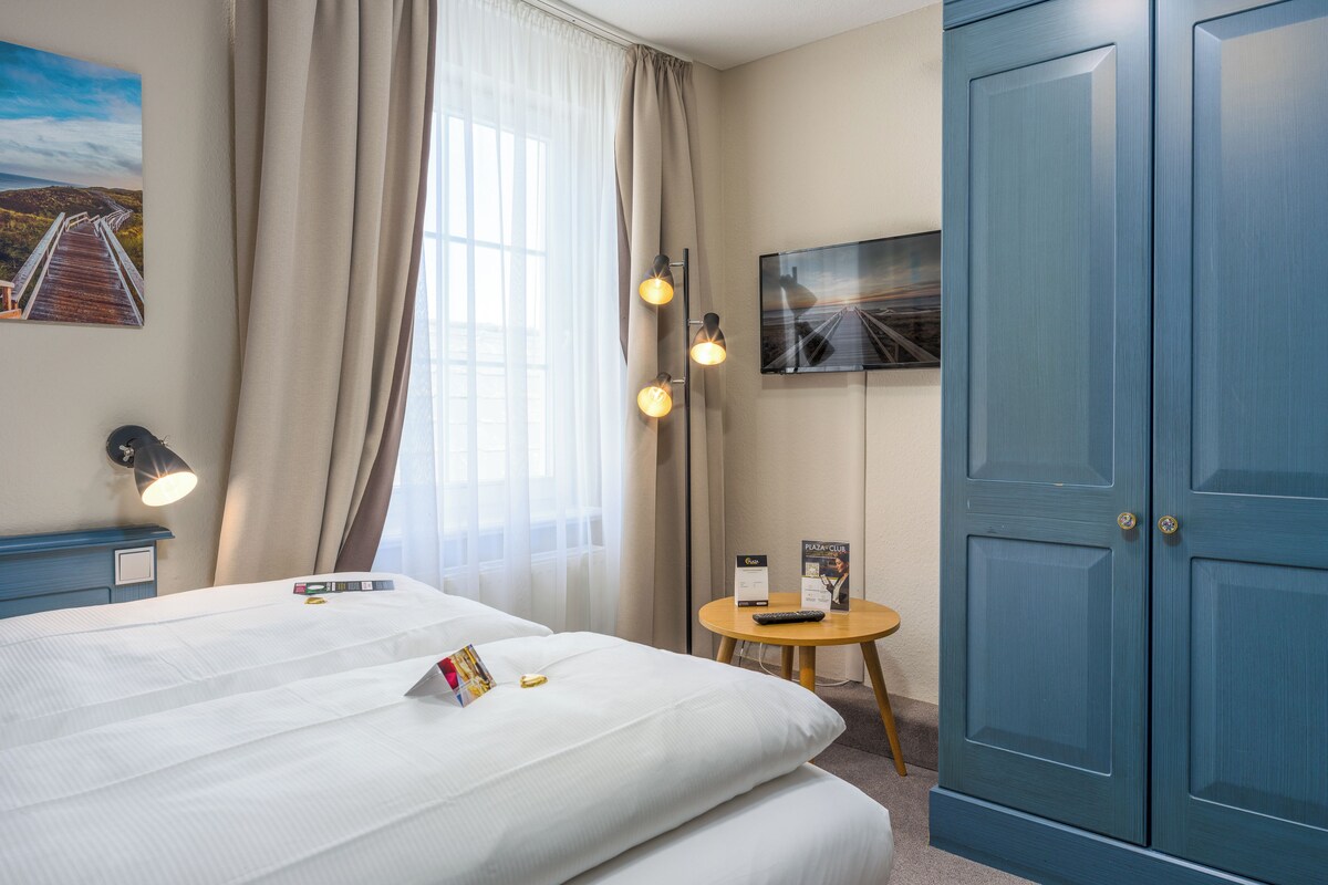 A hotel room with a bed, a desk, a television, and a wardrobe.