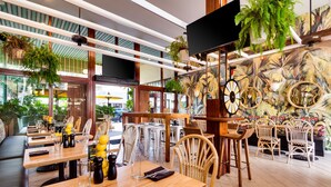 Ein Restaurant mit Holztischen, weißen Stühlen und einem Wandgemälde von tropischen Pflanzen.