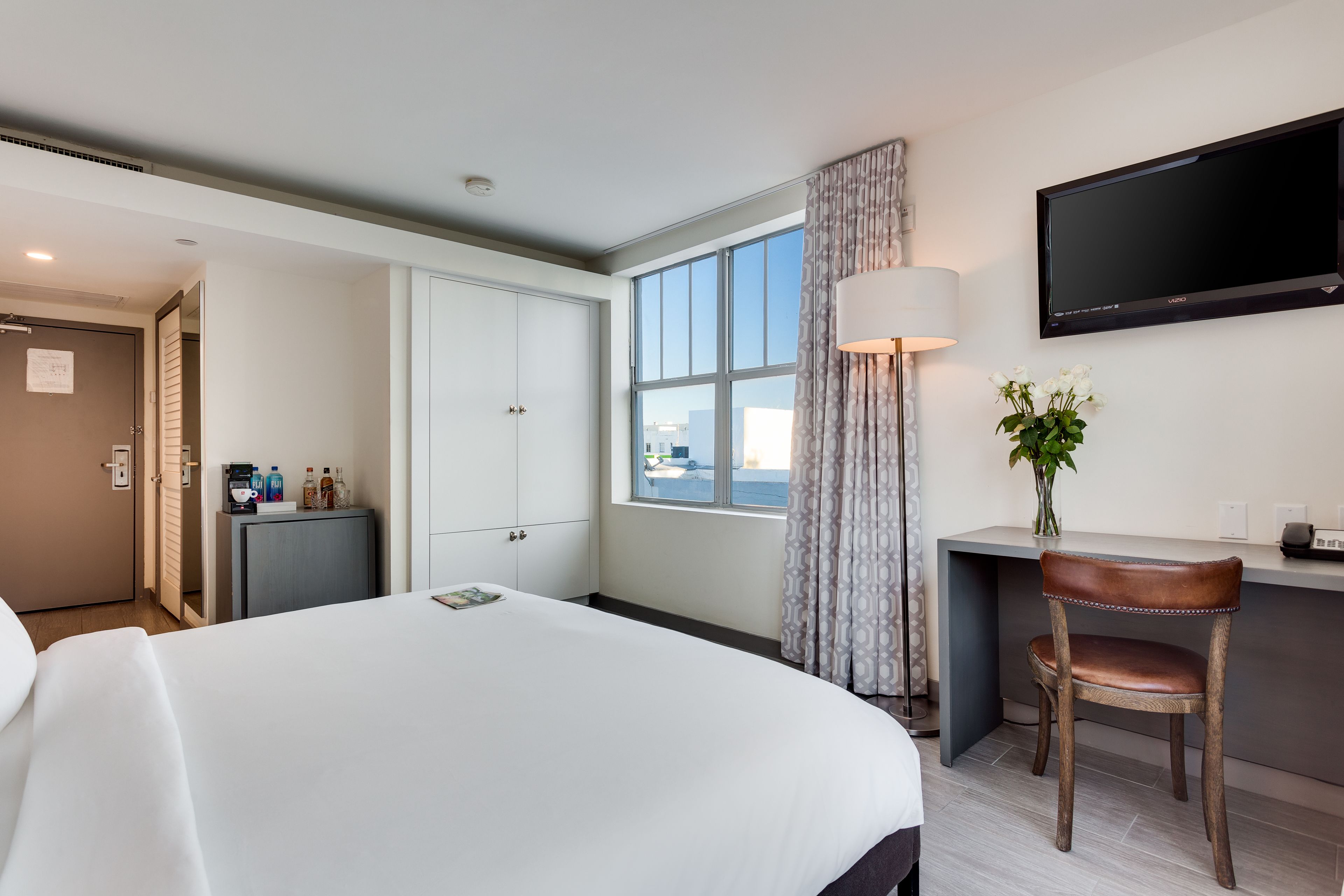 Een hotelkamer met een groot bed, een bureau met stoel, een flatscreen televisie en een raam met uitzicht op de stad.