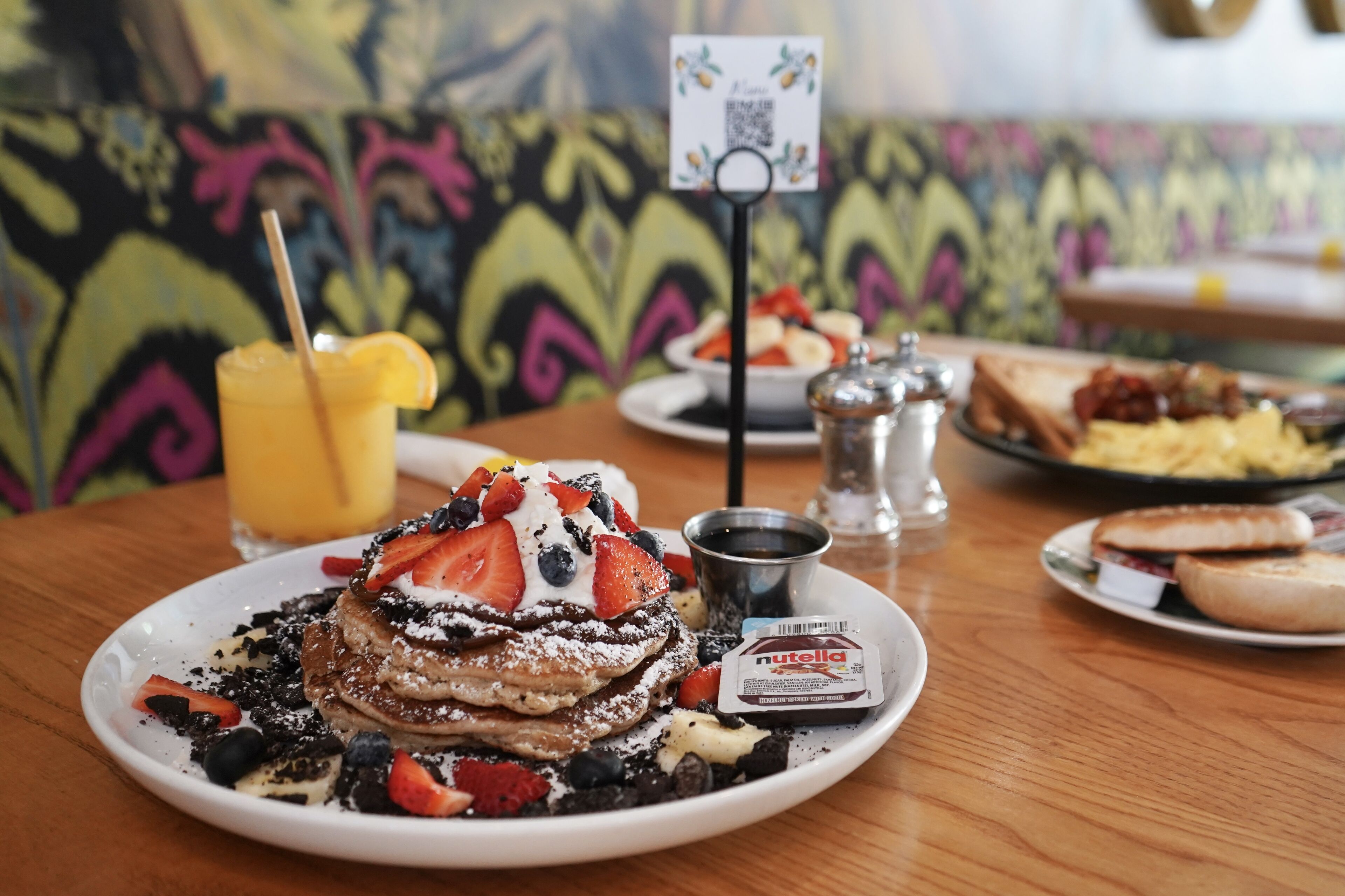 A breakfast plate with pancakes, strawberries, blueberries, and a Nutella packet.